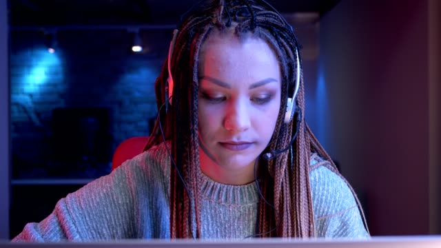 Closeup-shoot-of-young-attractive-female-blogger-with-dreadlocks-playing-video-games-and-streaming-live-with-the-neon-background-indoors
