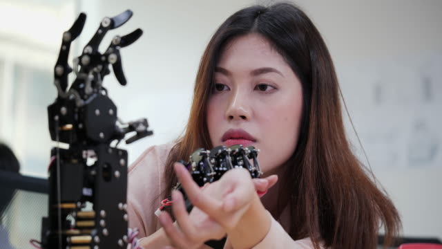 Asiatische-Tests-Cyborg-Hand-im-Labor.-Weiblich,-die-ihr-Roboterprojekt-macht,-testet-sensorsignal.-Technologie--und-Innovationskonzept.