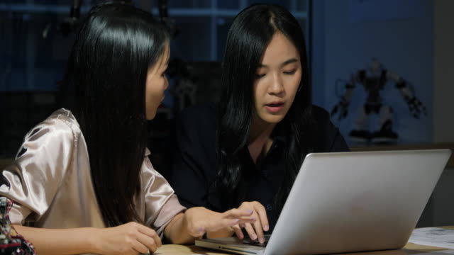 Asiatischer-junger-Elektronikingenieur,-der-Laptop-verwendet,-um-Informationen-zu-recherchieren,-um-Roboter-zusammen-zu-machen.-Technologie--und-Innovationskonzept.