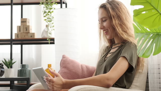 Chica-adolescente-feliz-usando-tableta-digital-en-el-sofá