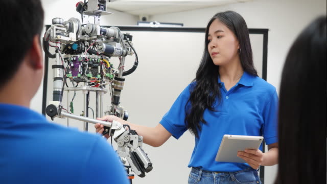 La-mujer-ingeniera-asiática-presenta-la-innovación-de-robots-con-el-equipo-de-diseño-de-arquitectos-en-laboratorio.-La-reunión-en-equipo-comparte-ideas-tecnológicas-y-un-robot-de-desarrollo-colaborador.-Concepto-de-tecnología-robótica-de-presentaci�