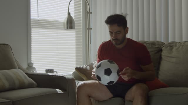 Slow-motion-of-man-playing-with-soccer-ball-at-home-gets-up-and-leaves