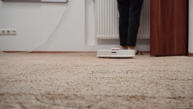 The-housewife-tidies-up-in-the-playroom.-The-robotic-vacuum-cleaner-cleans-the-carpet