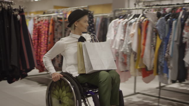 Glückliche-junge-Frau-im-Rollstuhl-Einkaufen-für-Kleidung