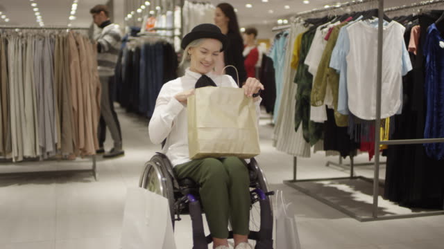Mujer-emocionada-en-silla-de-ruedas-posando-en-la-tienda-de-ropa