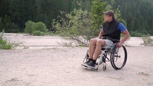 Slowmotion-of-disabled-young-student-man-in-a-wheelchair-observing-nature-around-him