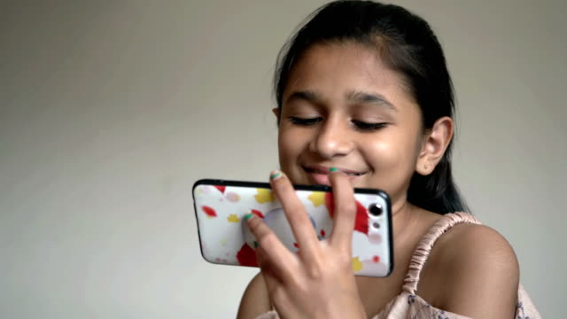 Niña-india-está-viendo-dibujos-animados-en-el-teléfono-inteligente