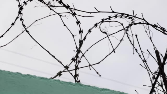 Close-up-view-of-prison-barbed-wire.-Barbed-wire-in-jail.-Fence-with-barbed-wire-against-grey-sky.