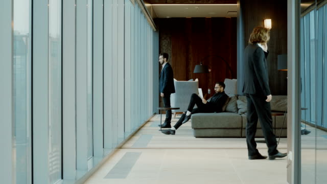 Three-men-in-black-suits-in-front-of-a-panoramic-window-of-modern-restaurant.-4K