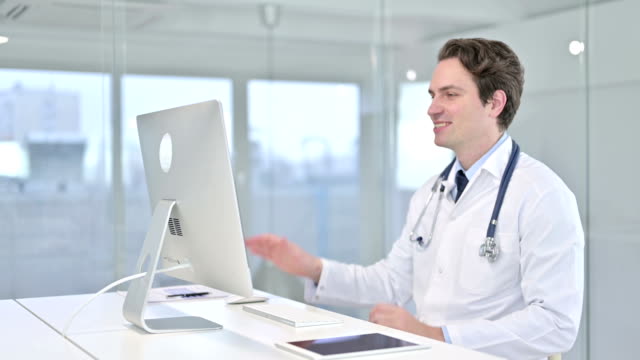 Fröhliche-junge-Arzt-tun-Video-Chat-auf-Schreibtisch-Top