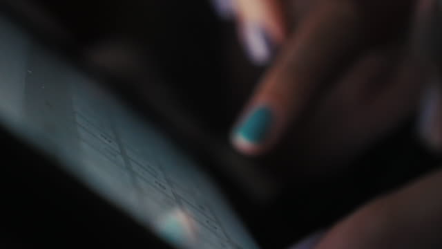 Nahaufnahme-der-Hände-einer-jungen-Frau-in-einem-dunklen-Raum,-um-Text-auf-dem-Touchscreen-des-Tablets-einzugeben