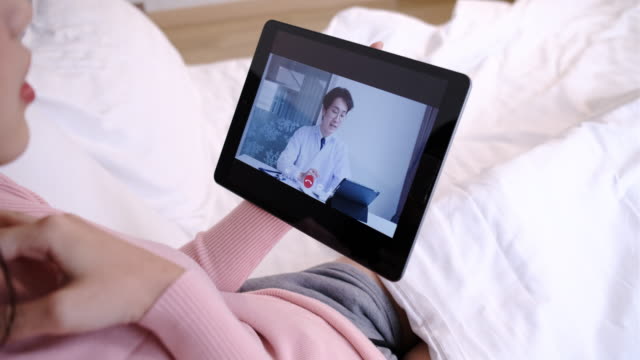 Interfaz-de-usuario-de-conexión-remota-de-la-joven-mujer-asiática-hablando-con-el-médico-en-línea-en-la-tableta.-El-médico-explicó-cómo-llevar-el-medicamento-al-paciente-por-videollamada.