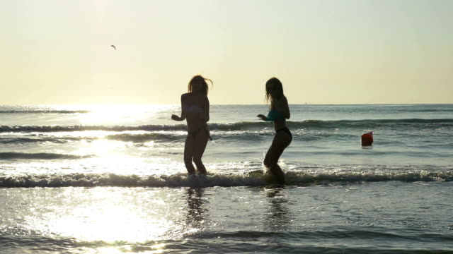 Silhouettes-of-two-women-dancing-on-the-shore-of-a-sandy-beach