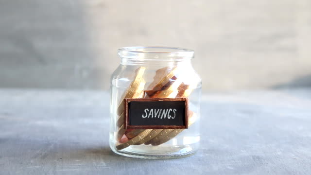 savings-idea,-vintage-tag-and-coins-in-jar