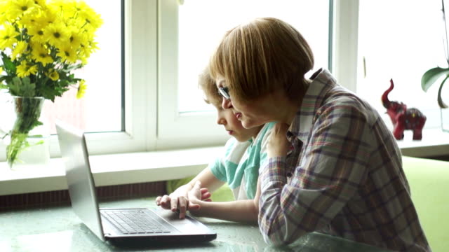 Die-Großmutter-und-der-Enkel-mit-Interesse-schauen-auf-den-Laptop-Bildschirm.