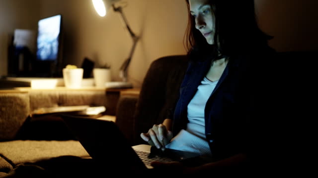 Junge-hübsche-Frau-mit-Laptop-Computer-und-Surfen-social-Media-in-der-Nachtzeit-auf-Trainer-zu-Hause-sitzen