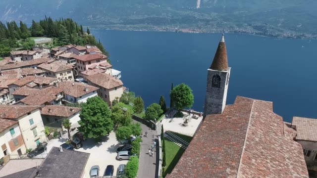 Italien.-Kirche-auf-dem-Berg-und-der-Altstadt-entfernt.-Panorama-des-wunderschönen-Gardasees-umgeben-von-Bergen.-Videodreh-mit-Drohne