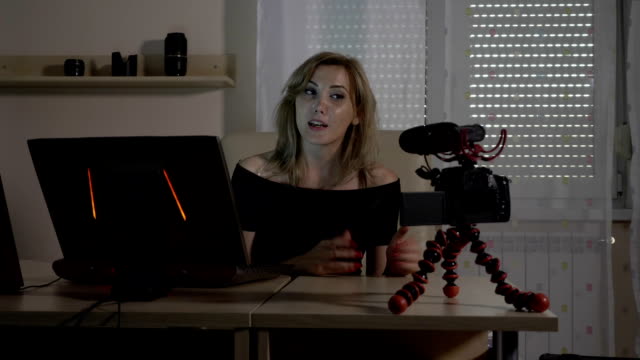 Rubia-atractiva-mujer-video-blogger-a-filmar-con-una-cámara-en-la-oficina-enseñando-a-audiencia-analizar-los-datos-de-tráfico