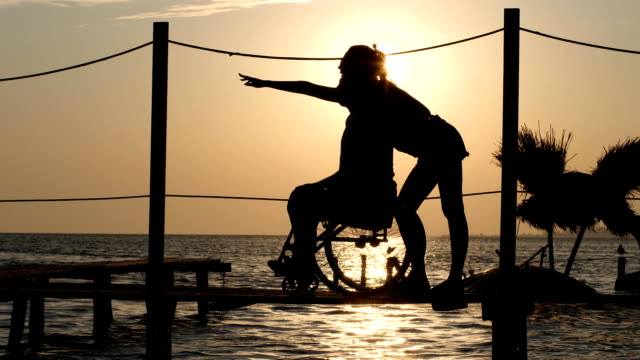 Chica-feliz-discapacitados-mirando-en-horizonte-sobre-fondo-de-puesta-de-sol-en-el-agua-en-el-viaje-de-verano
