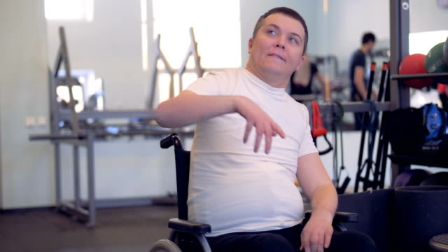 A-disabled-man-is-stretching-his-arms-and-shoulders-while-sitting-in-a-wheelchair