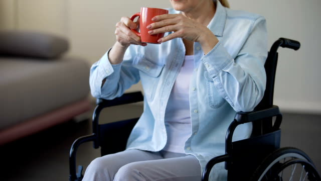 Mujer-Senior-en-silla-de-ruedas-bebiendo-té,-relajarse-en-el-hogar-del-pensionista,-ocio