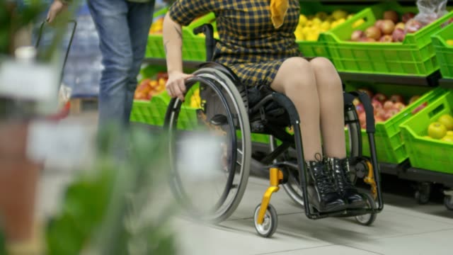 Mujer-a-caballo-para-sillas-de-ruedas-en-producir-pasillo-mientras-compras-con-marido