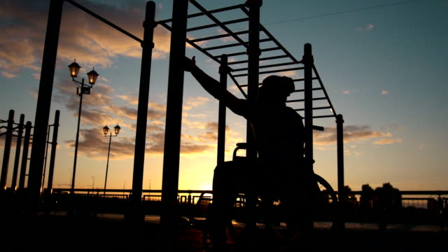 Silueta-de-hombre-joven-con-discapacidad-levantado-sobre-las-barras-transversales-en-la-puesta-de-sol-al-aire-libre