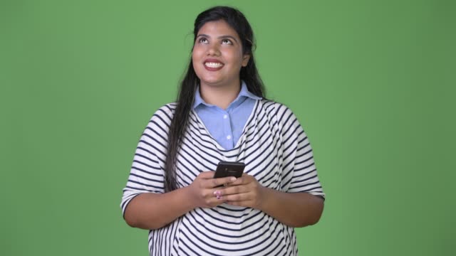 Young-overweight-beautiful-Indian-businesswoman-against-green-background