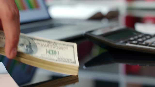 Hand-giving-dollar-bills-on-office-table.-Bank-offers-instant-money-transfer