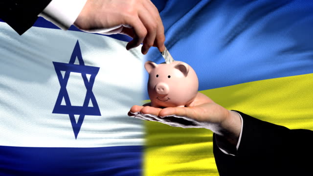 Israel-investment-in-Ukraine,-hand-putting-money-in-piggybank-on-flag-background
