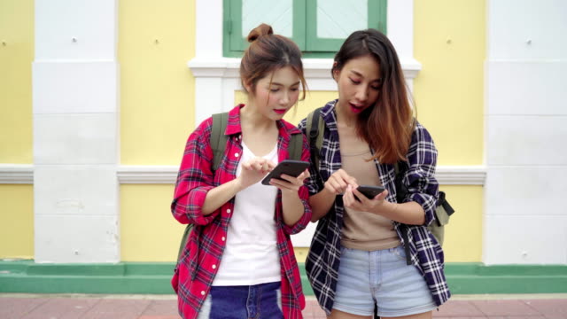 Traveler-backpacker-Asian-women-lesbian-lgbt-couple-travel-in-Bangkok,-Thailand.-Happy-young-female-direction-and-looking-on-location-map-on-smartphone.