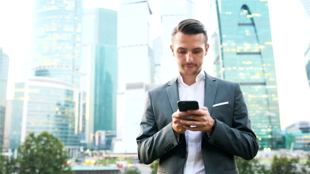 Kaukasischen-Jüngling-Smartphone-für-Business-Arbeit-halten.