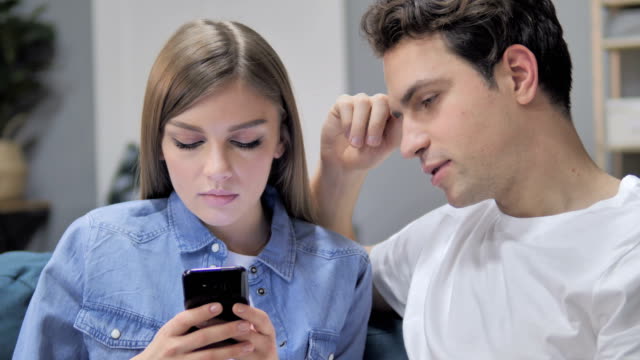 Hablando-joven-pareja-con-Smartphone-y-productos-en-línea-Disussing