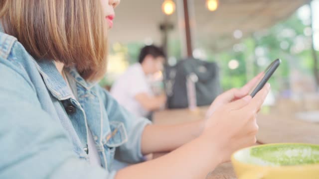 Freie-asiatische-Geschäftsfrau-mit-Smartphone-zum-sprechen,-lesen-und-SMS-beim-Sitzen-am-Tisch-im-Café.-Lebensstil-smart-schöne-Frauen-arbeiten-bei-Coffee-Shop-Konzepte.