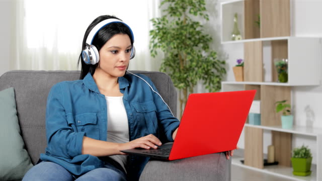 Mujer-con-auriculares-viendo-el-contenido-del-ordenador-portátil-en-casa