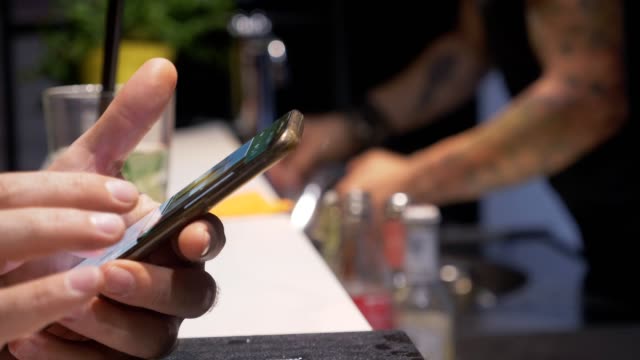 caucasian-man's-hands-surfing-on-smartphone-at-bar-counter--close-up
