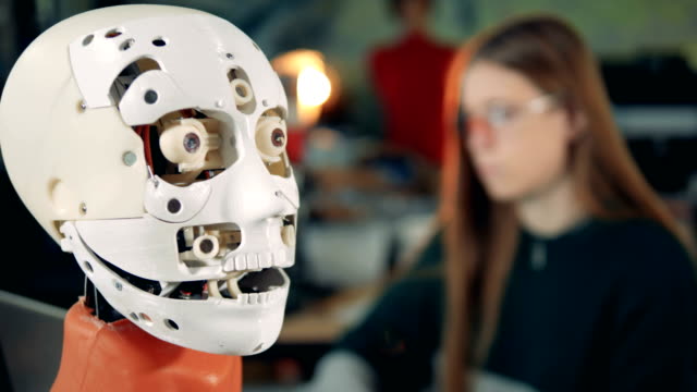 Roboter-Kopf-öffnet-seinen-Mund-unter-Aufsicht-eines-weiblichen-Experten