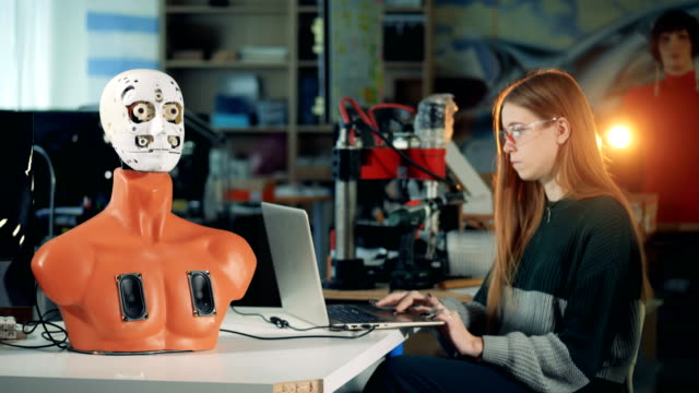 Menschenähnliche-Roboter-bewegt-seinen-Mund-unter-Kontrolle-einer-jungen-Frau