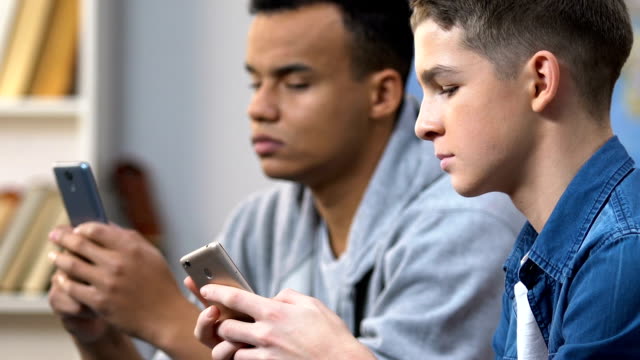 Zwei-High-School-Jungs-durchsuchen-Social-Media-Website-auf-Smartphones,-mobile-Sucht