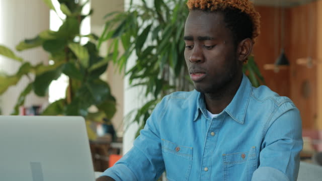 Afrikanischer-amerikanischer-Mann,-der-Laptop-Computer-im-Café-benutzt,-um-Geschäftsideen-zu-teilen