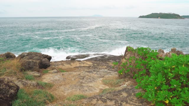 tropical-island-in-the-distance-from-the-shore-through-the-Strait.-sea-waves-break-on-the-shore,-rest-and-travel