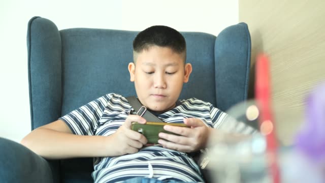 Young-teenager-playing-game-on-smartphone-in-cafe