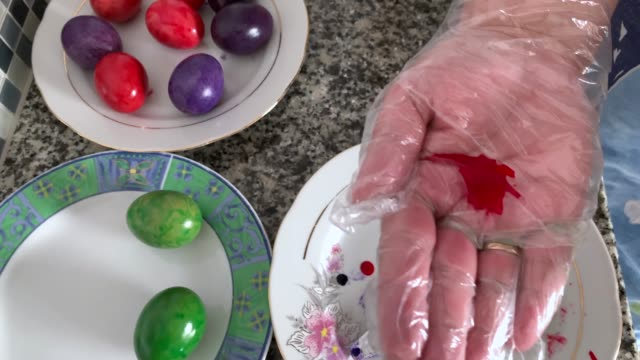 A-woman-in-gloves-paints-eggs
