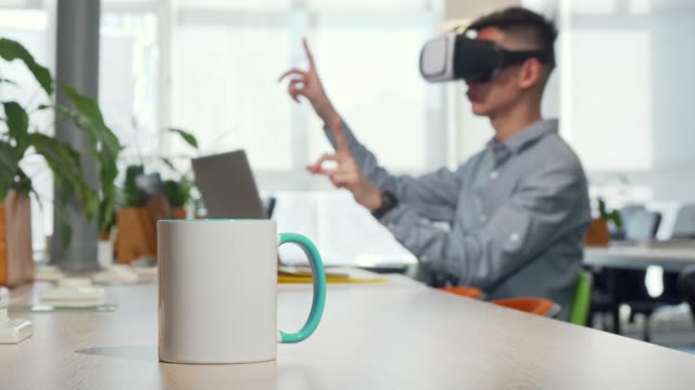 Cup-of-coffee-on-the-table,-man-using-3d-vr-glasses-at-work-on-the-background