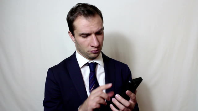 Young-handsome-businessman-pulls-out-his-smartphone-from-his-pocket-and-looks-through-the-news-feed.