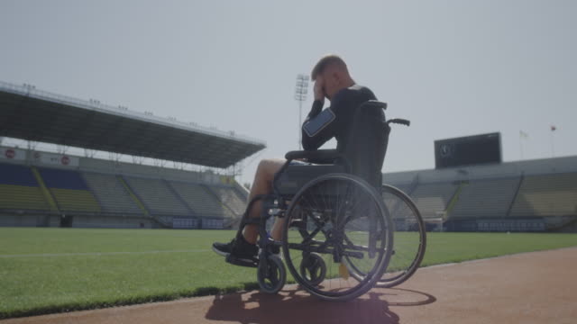 Atleta-discapacitado-sentado-en-silla-de-ruedas-junto-a-un-campo-deportivo