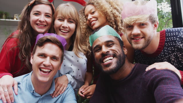 Group-Of-Friends-Enjoying-Christmas-Party-At-Home-Together-Taking-Selfie