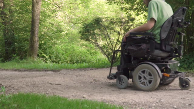 Lento-movimiento-del-hombre-en-una-silla-de-ruedas-que-sale-de-la-carretera-con-obstáculo-en-la-carretera.-discapacitados-concepto-problema