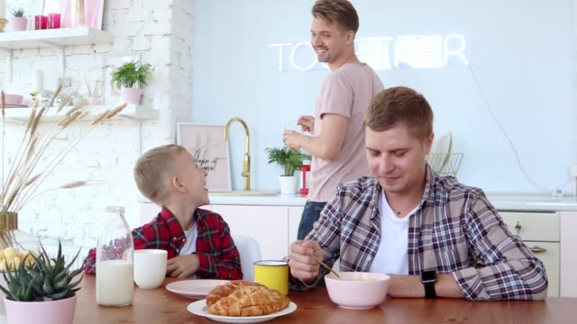 Happy-gay-family-two-fathers-and-son-are-having-breakfast-in-the-kitchen.
