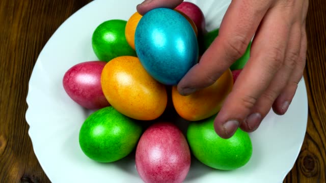 Hand-legt-auf-einem-Teller-die-Ostern-geschmückt-und-bemalt-farbigeei-während-einer-Auferstehung-Sonntag-oder-Pascha